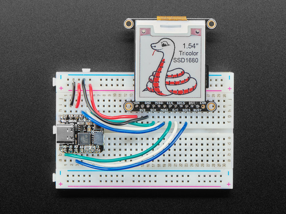 Video of a 1.54" tri-color eInk display assembled on a breadboard with jumper wires and a QT Py. Friendly snake in white-and-red, Blinka, appears on the display.