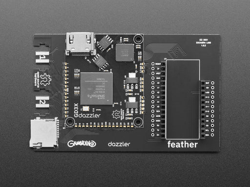 A small monitor and a Gameduino Dazzler PCB with a Feather M4 Express. The monitor displays a swirling kaleidoscopic animation with CircuitPython and Blinka, a friendly coding python.