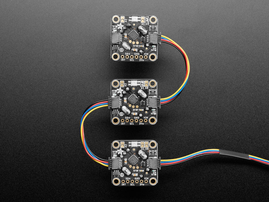 Top view video of a gloved hand turning the rotary encoder knobs on three PCBs. The NeoPixel LEDs on each PCB change color. The OLED display changes its readout data with each twisty-turn.