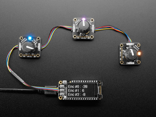 Top view video of a gloved hand turning the rotary encoder knobs on three PCBs. The NeoPixel LEDs on each PCB change color. The OLED display changes its readout data with each twisty-turn.