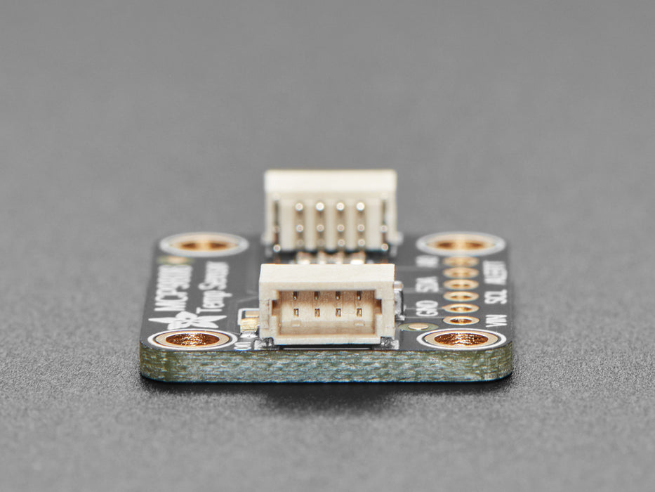 Top view of temperature sensor breakout above an OLED display FeatherWing. The OLED display reads "MCP9808 Temp: 24.19��C"