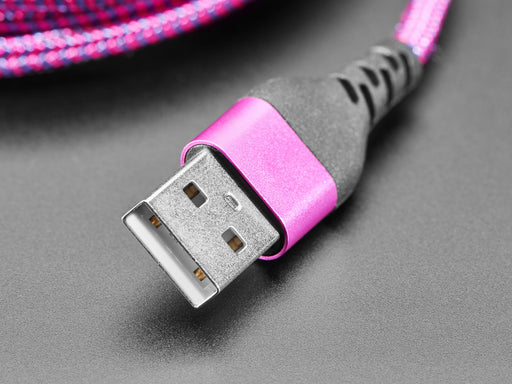 Angled shot of a pink/purple woven USB cable plugged into a laptop port and a small dev board.