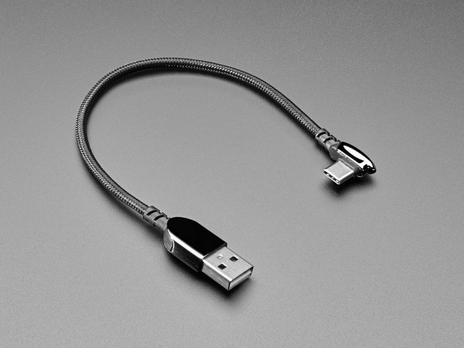 Angled shot of a black woven USB cable plugged into a laptop port and a small dev board.