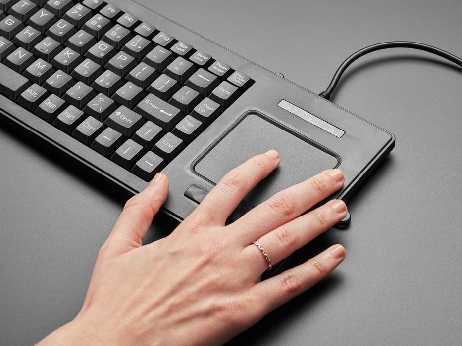 Top view of a white woman's hands typing on full-size keyboard with trackpad.