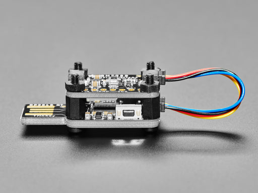 Angled shot of a USB key-shaped PCB with a sensor board stacked on top via black nylon screws.