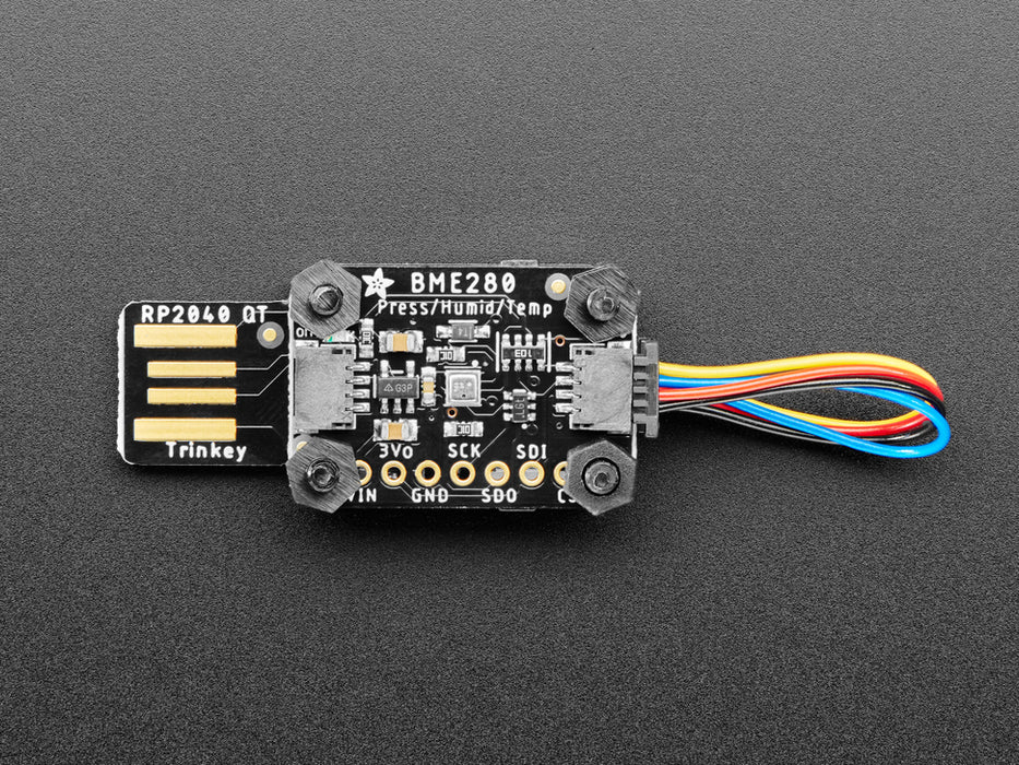 Angled shot of a USB key-shaped PCB with a sensor board stacked on top via black nylon screws.