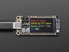 Adafruit ESP32-S2 TFT Feather powered on by a USB- C power source displaying the product tittle in a red, yellow, green, white and blue. 