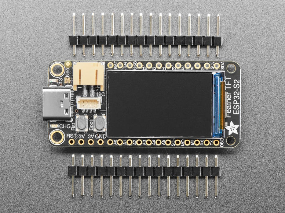 Adafruit ESP32-S2 TFT Feather powered on by a USB- C power source displaying the product tittle in a red, yellow, green, white and blue. 