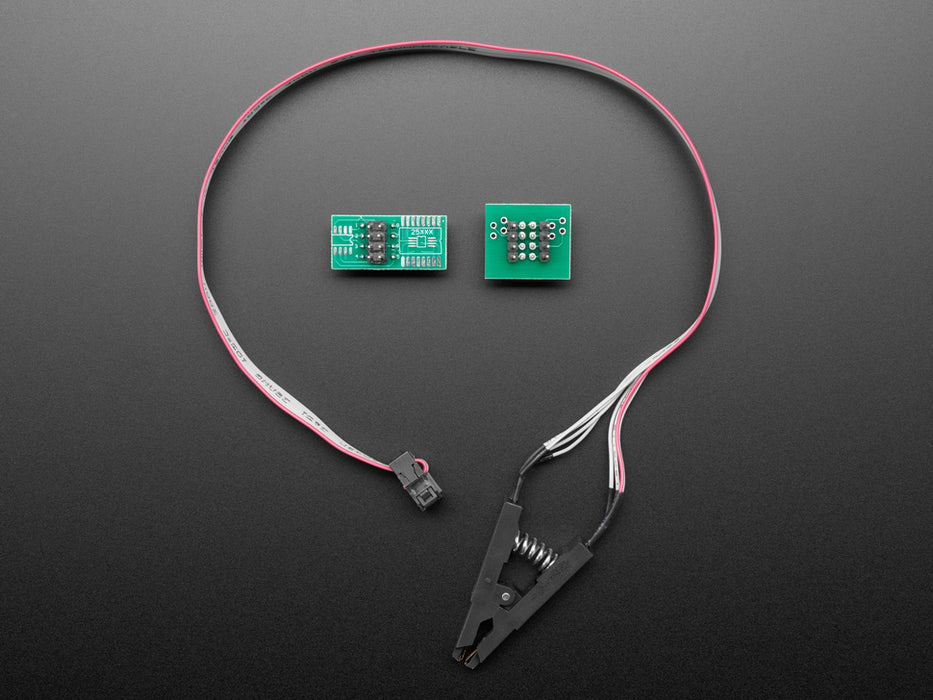 probe clip with cable attached to a SOIC chip on a pink PCB.