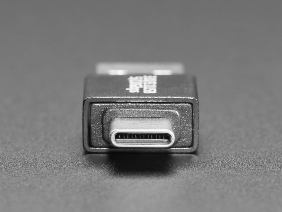 Angled video of a USB adapter plugged into a laptop. A square-shaped microcontroller is plugged into the other end of the adapter. An RGB LED on the microcontroller emits a rainbow spectrum of colors.