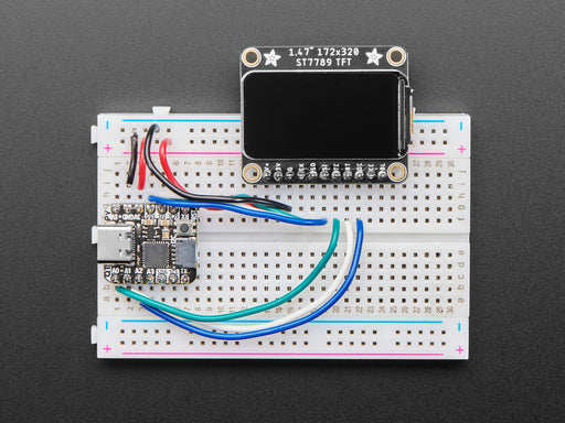 TFT display breakout soldered and assembled onto a half-size breadboard and wired up to a microcontroller. The color TFT screen displays a boot-up screen.