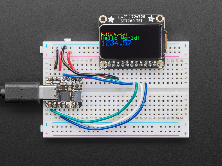 TFT display breakout soldered and assembled onto a half-size breadboard and wired up to a microcontroller. The color TFT screen displays a boot-up screen.