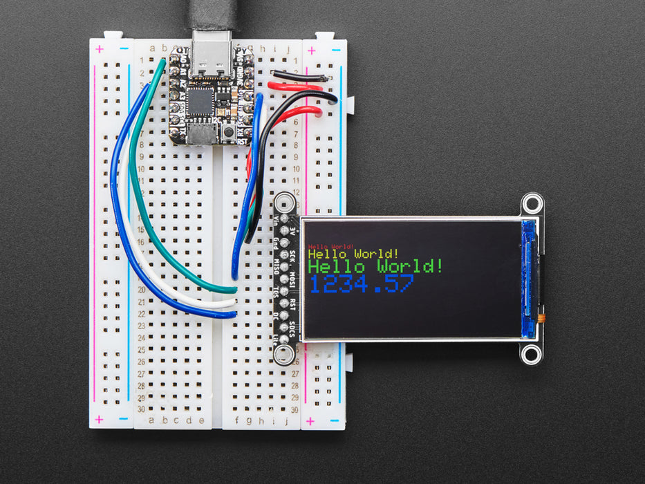 TFT display breakout soldered and assembled onto a half-size breadboard and wired up to a microcontroller. The color TFT screen displays a cycle of animations.