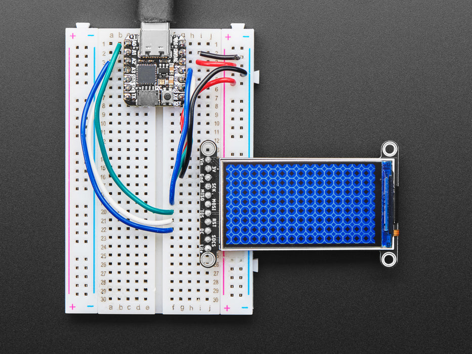 TFT display breakout soldered and assembled onto a half-size breadboard and wired up to a microcontroller. The color TFT screen displays a cycle of animations.