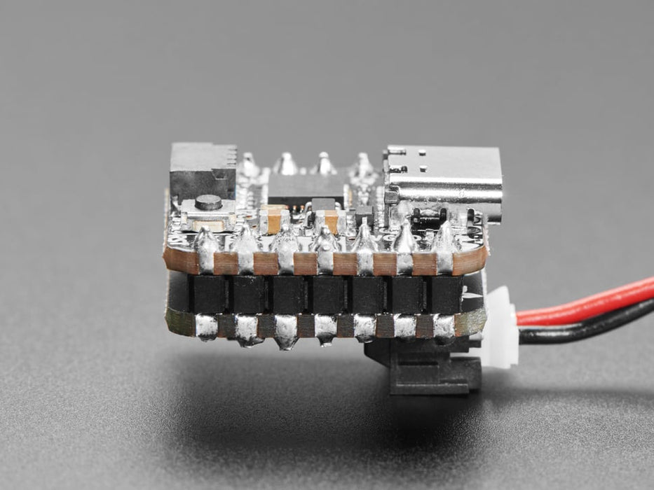 Video of a person with white painted nails unplugging a USB cable from a small, black, square-shaped lipo battery breakout board soldered to a similarly shaped microcontroller, which is also connected to a monochrome OLED display breakout. The OLED breakout displays battery and power data.