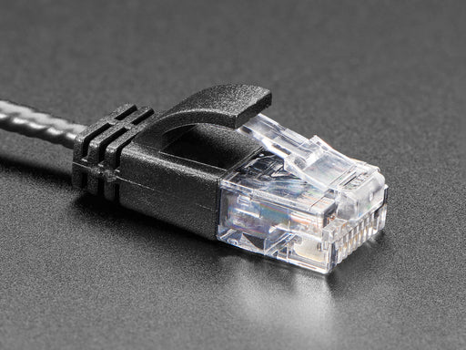 Angled shot of a black coiled Ethernet cable with RJ-45 connectors on both ends.