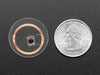 Bottom of small, clear, circular NTAG203 (13.56MHz RFID/NFC) tag next to US quarter for scale.