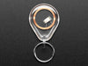 Overhead shot of a clear keychain fob with an RFID/NFC NTAG203 tag inside placed next to a US quarter for scale.