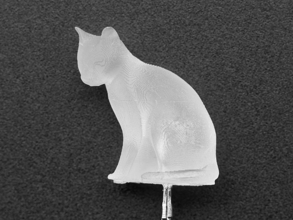 Close-up video of a cat-shaped LED. The LED glows a spectrum of white to green to purple light.