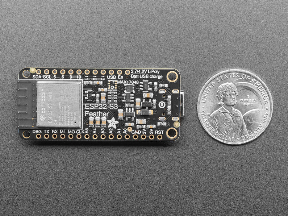 Top view of a purple rectangular microcontroller with a color TFT screen and powered by an ESP32-S3 chip. It is also connected to a Li-Poly battery and a lux sensor breakout. The TFT display reads in colored text: "Adafruit Feather
ESP32-S3 TFT Demo
Battery: 3.8V / 45%
I2C: 0xB, 0x10, "