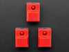 Angled shot of three red plastic step-switches with red LEDs.