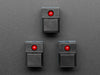 Angled shot of three black plastic step-switches with red LEDs.