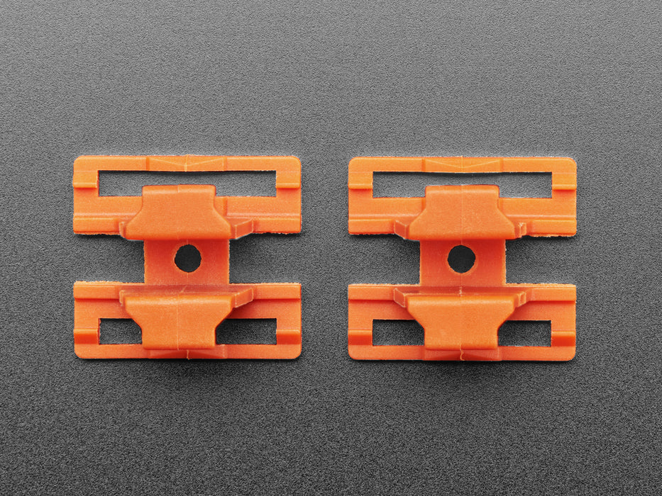 Angled shot of two orange plastic buckles assembled with two different wiring block connectors.