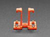 Angled shot of two orange plastic buckles assembled with two different wiring block connectors.