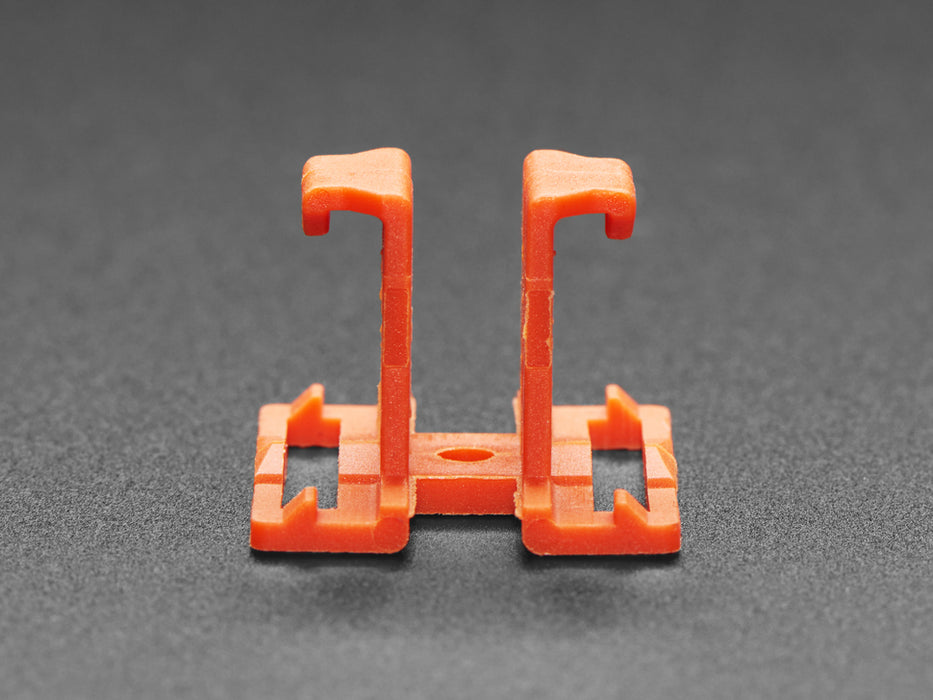 Angled shot of two orange plastic buckles assembled with two different wiring block connectors.