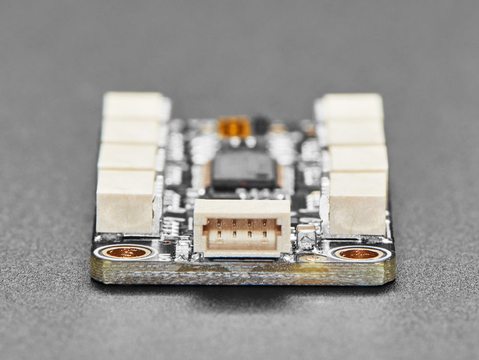 Overhead shot of STEMMA QT breakout board with eight JST-SH ports wired up to four black, rectangular VCNL light sensors. All their indicator LEDs are lit up green.