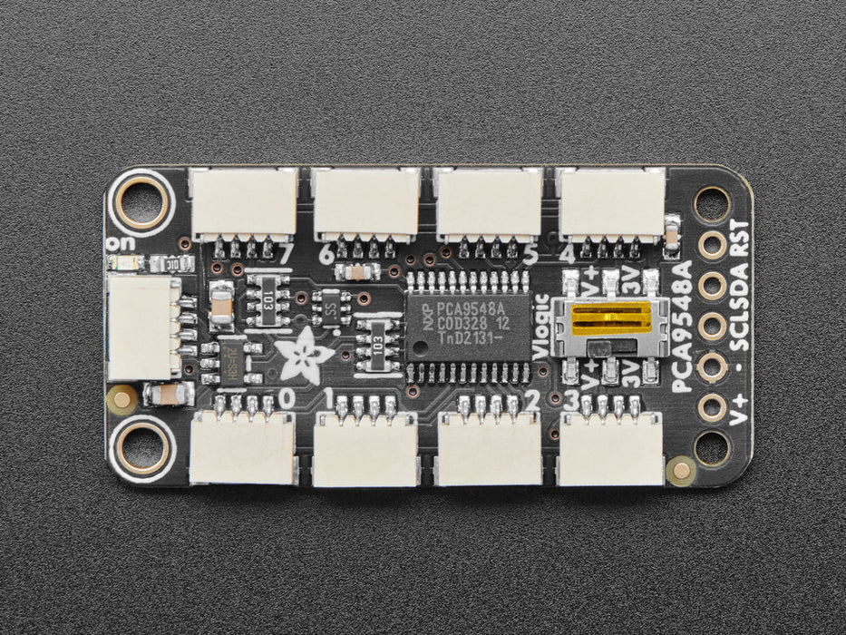 Overhead shot of STEMMA QT breakout board with eight JST-SH ports wired up to four black, rectangular VCNL light sensors. All their indicator LEDs are lit up green.