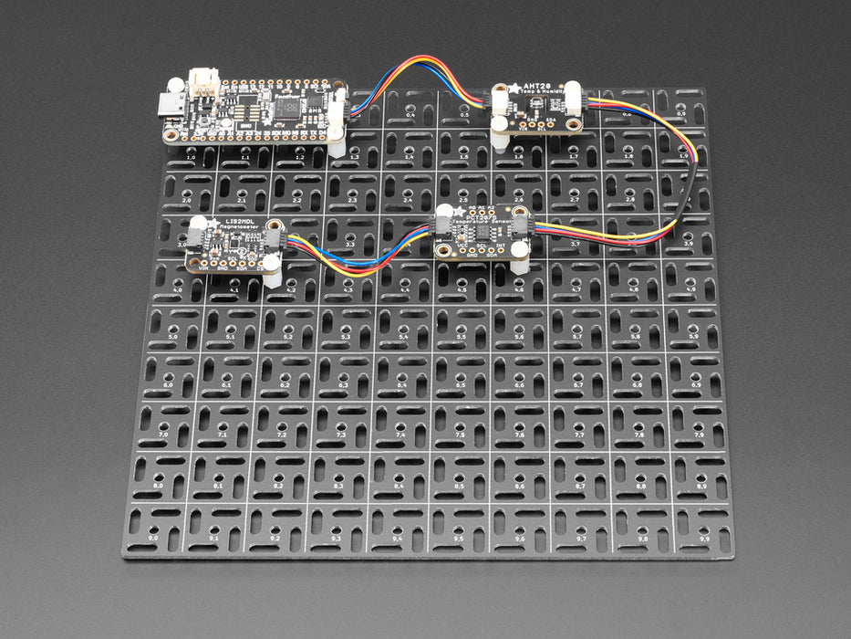 Overhead shot of 10x10 aluminum prototyping grid with a microcontroller and three breakout boards.