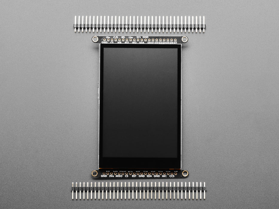 Overhead shot of a Black woman's green-manicured hand touching a 3.5" TFT display breakout connected to a small, square-shaped microcontroller. The TFT screen displays a drawn red heart.