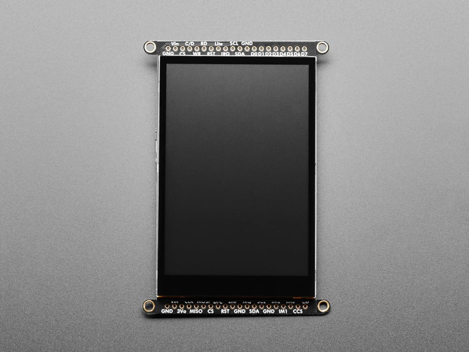 Overhead shot of a Black woman's green-manicured hand touching a 3.5" TFT display breakout connected to a small, square-shaped microcontroller. The TFT screen displays a drawn red heart.