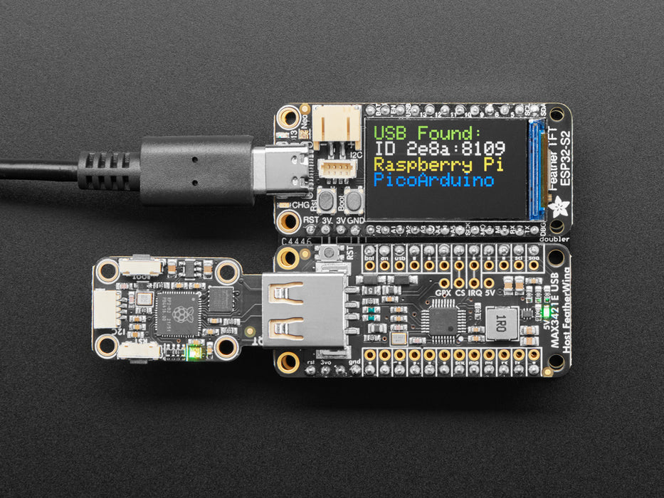 Video of a Black woman's green-manicured hand plugging in a USB TrinKey board into a USB Host FeatherWing assembled on a Doubler below an Adafruit TFT microcontroller board.