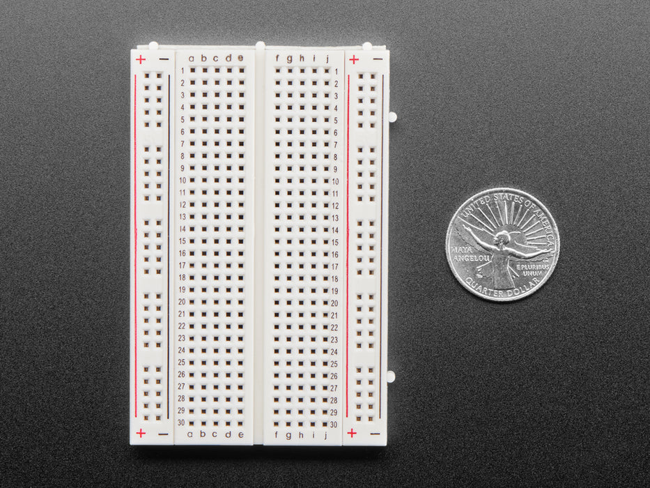 Angled shot of half-size solderless breadboard with red and black power lines.