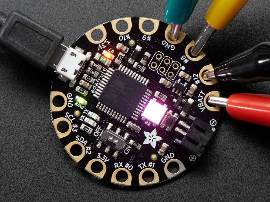 Top down view of a FLORA - Wearable electronic platform: Arduino-compatible connected to 4 alligator clips and a USB powerin the FLORA. 