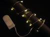 Coil of thin flexible wire with lit up embedded LED 'fairy' lights attached to battery holder