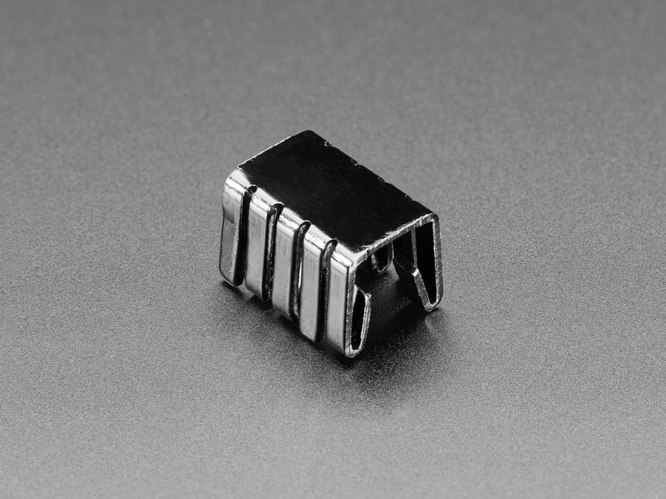 Clip on bent metal heat sink on top of a transistor, plugged into breadboard.